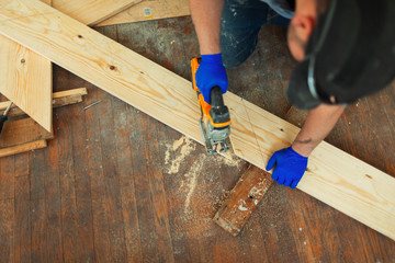 Carpenter cutting wood with saw at construction site