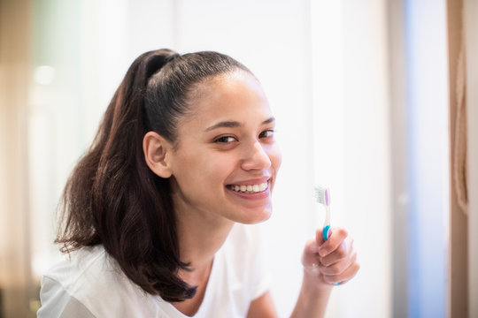 Portrait smiling, confident woman brushing teeth in bathroom mirror