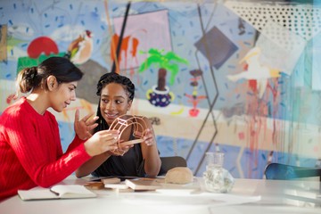 Female engineers examining prototype in creative conference room
