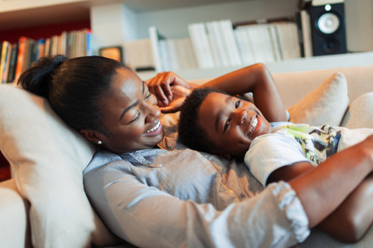 Portrait happy, affectionate mother and son cuddling on living room sofa