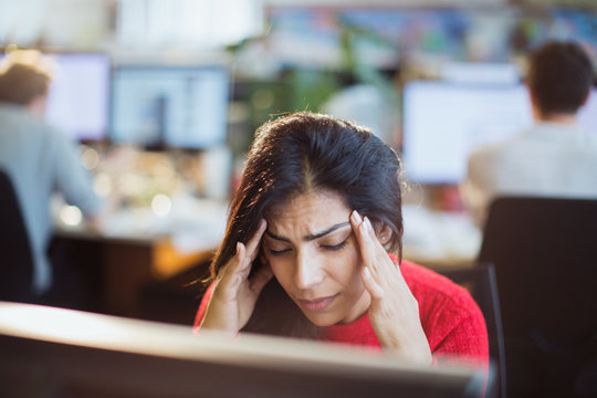 Stressed businesswoman with head in hands at computer in office