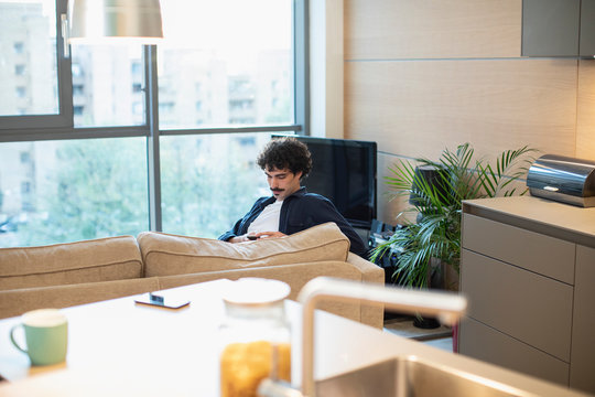 Man using smart phone on urban apartment sofa