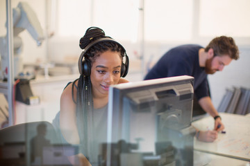 Female engineer with headphones using computer in office