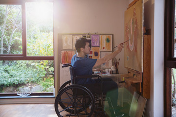 Male artist in wheelchair painting in art studio
