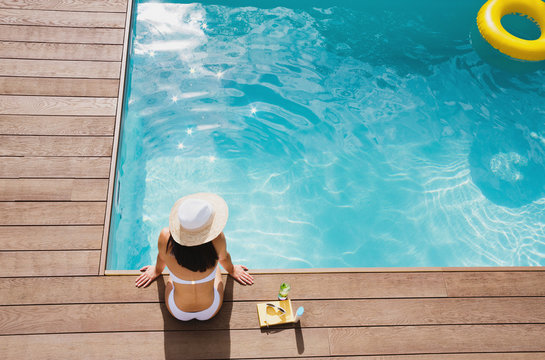 Woman in sun hat relaxing at sunny summer poolside