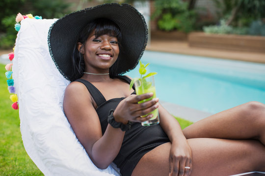 Portrait beautiful young woman relaxing with cocktail at poolside
