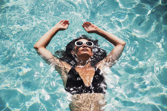 Serene woman floating in sunny summer swimming pool
