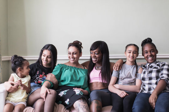 Portrait lesbian couple with children on living room sofa