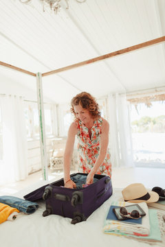 Woman unpacking suitcase in beach hut bedroom