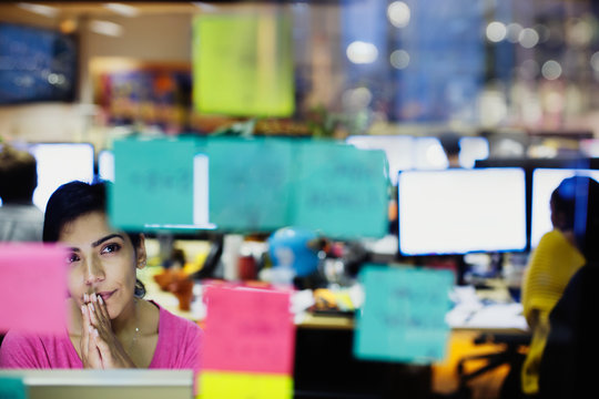 Thoughtful businesswoman looking at adhesive notes, planning in office