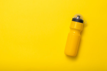 Yellow sports water bottle on yellow background. Flat lay.