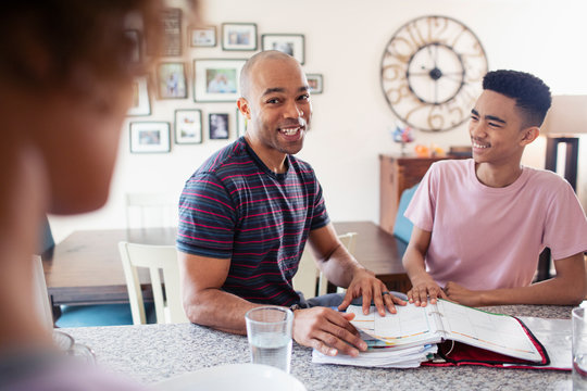 Father helping son with homework in kitchen