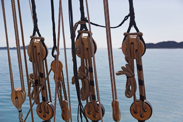 Wooden sailboat pulleys and rigging on ocean
