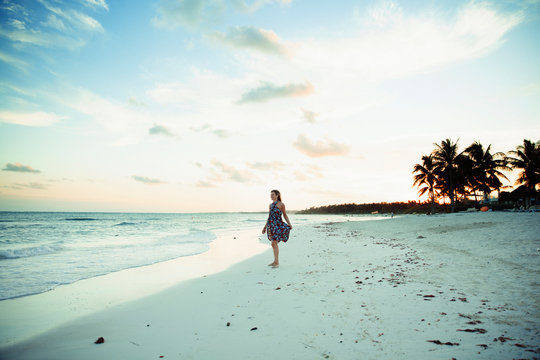 Carefree woman in sun dress on tropical ocean beach Mexico