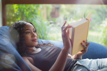 Young woman relaxing reading book in beanbag chair