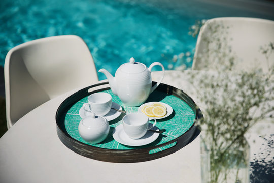 Tea service on sunny poolside patio table