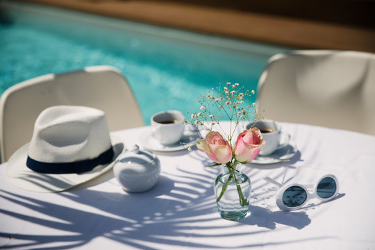 Roses and coffee on sunny poolside patio table