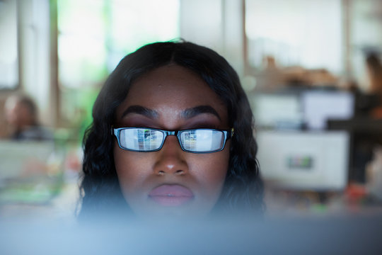 Focused young businesswoman in eyeglasses working at computer