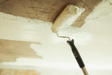 Paint roller painting ceiling white