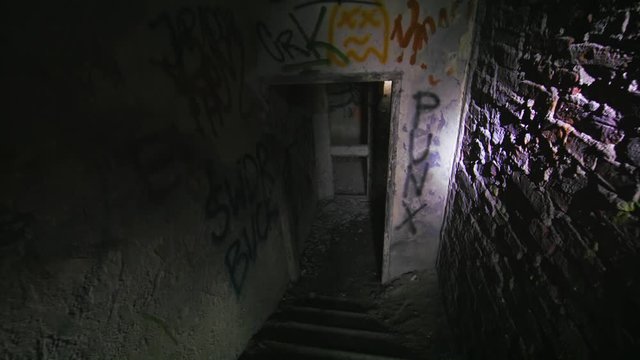 Dark, claustrophobic, hallow stairway in an abandoned building. Flashlight light on the walls falling apart. Horror filming location