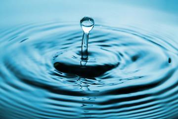 Closeup Water drop falling on the surface of the water and beautiful circular wave ripple, fresh natural mineral water drink water concept