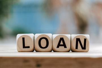 LOAN concept with wooden block on wooden table background.