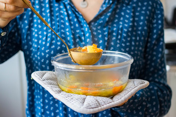 Woman hands holds vegetable soup with dipper in glass bowl. Vegan and vegetarian food