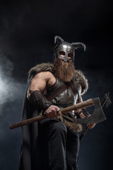 Warrior Viking in full arms with axe and shield on dark background