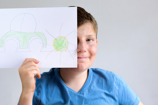 Boy holding drawing of car and sun