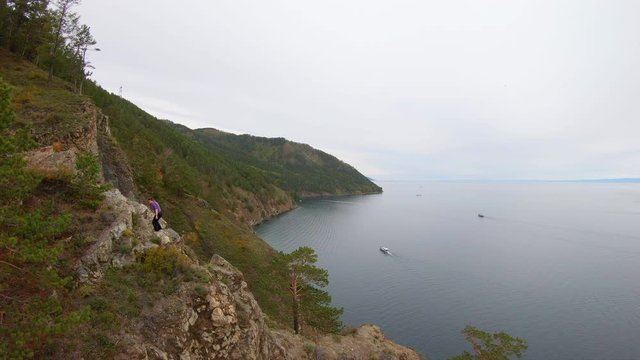 Aerial view of climbing up the cliff on a rocky shore of lake Baikal. Drone flying above the coast