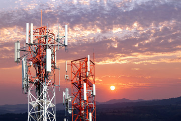 Telecommunication antennas tower on sunset background.