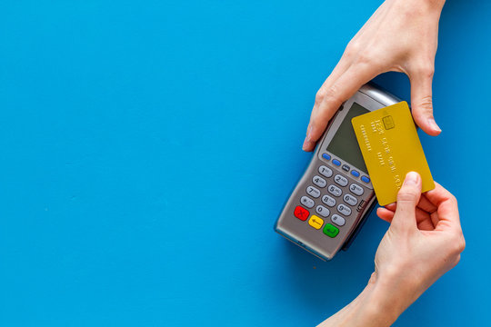 Contactless payment, paypass. Hand hold bank card near terminal on blue background top-down copy space