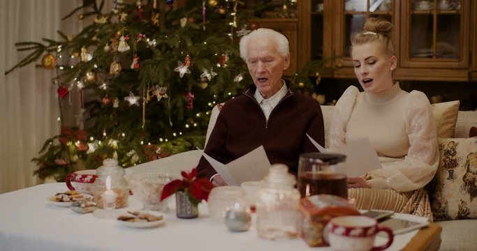 Grandfather And Granddaughter Caroling At Home