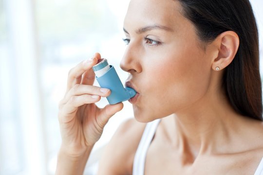 Young woman using an inhaler