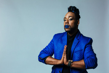 Studio portrait of a man with blue outfit and blue lips. Meditating