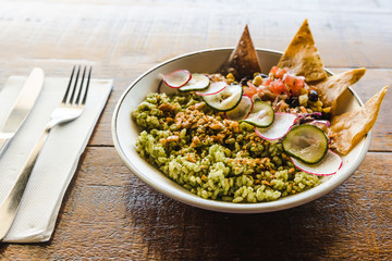 pesto rice with mixed beans and tortilla chips in a buddha bowl