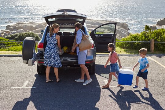 Family Unpacking The Car By The Beach