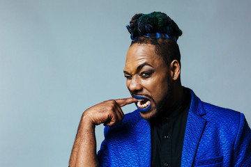 Studio portrait of a man with blue outfit and blue lips.