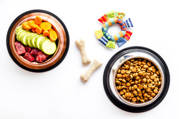 Dog feed - dry food and raw meat - near toy and cheving bones on white background top view copy space