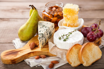 Cheese, honey and fruit on a table. Selective focus. Copy space.
