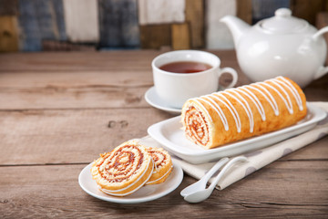 Swiss roll with jam and tea on a table. Selective focus. Copy space.