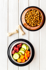 Ingredients of dry feed for dogs - meat, vegetables - near bones on white wooden background top view