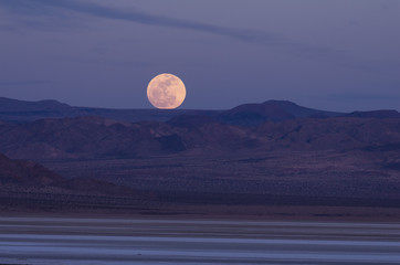 Full moon rising over mountains in the Mojave Desert, California, United States. © angeldibilio