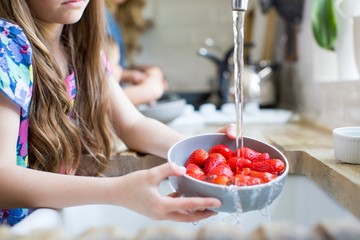 Girl washing fresh strawberries