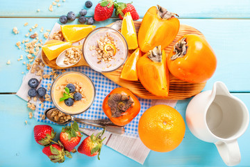 Orange persimmon blueberry smoothie with granola  and fruits. Selective focus. Copy space. Top view