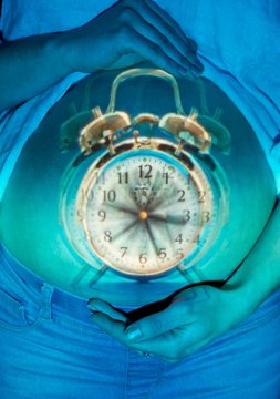Pregnant woman holding alarm clock