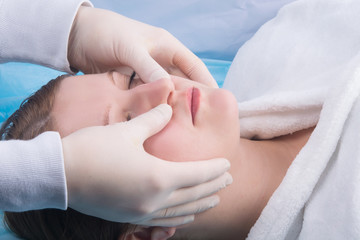 woman, in a white coat, doing facial massage at Spa treatments, close-up