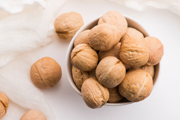 Walnuts in a white ceramic bowl on a white background