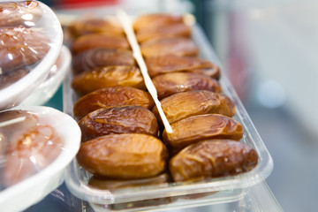 Dried dates are laid in a plastic tray in two even rows.