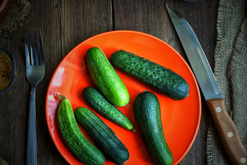 Cucumbers on a colored plate. On a wooden kitchen table.